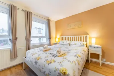 a bedroom with a bed and two windows at Sunny Cottage in Keswick