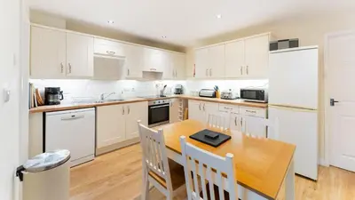 a kitchen with a wooden table and white appliances at Sunny Cottage in Keswick