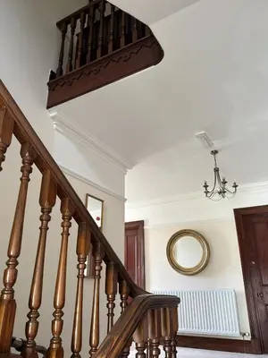 a stairway with a wooden rail and a round mirror at Thwaite Howe in Keswick