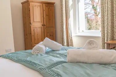 a bed with towels on top of it with a window at Thwaite Howe in Keswick