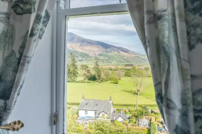 a window with a view of a house and a field at Thwaite Howe in Keswick