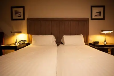 a bedroom with two beds and two lamps and a headboard at Strathaven Hotel in Strathaven