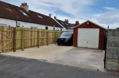 a garage with a car parked next to a fence at Harling House - Prestwick - 4 bedrooms in Prestwick