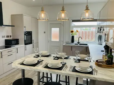 a kitchen with a table with plates and wine glasses at Harling House - Prestwick - 4 bedrooms in Prestwick