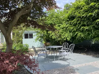 a patio with a table and chairs under a tree at Glenn Cottage in Braithwaite