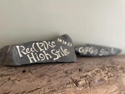 two rocks with writing on them sitting on a log at Glenn Cottage in Braithwaite