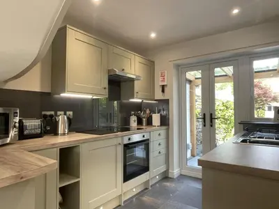 a kitchen with white cabinets and a large window at Glenn Cottage in Braithwaite
