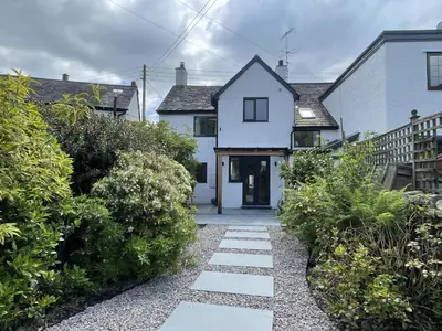 a white house with a pathway leading to the front door at Glenn Cottage in Braithwaite