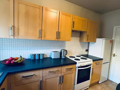 a kitchen with wooden cabinets and a bowl of fruit on the counter at Cumberland House-2 Bedrooms - Sleeps 4 in Workington