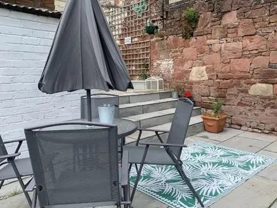 a table with an umbrella and two chairs and a table with a television at Reed Cottage in Aspatria