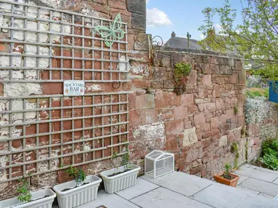 a brick wall with four pots of plants in it at Reed Cottage in Aspatria