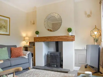 a living room with a fireplace and a couch and a mirror at Reed Cottage in Aspatria