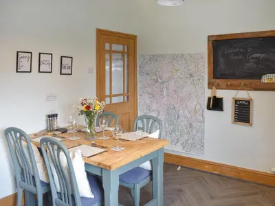 a dining room with a table with chairs and a chalkboard at Reed Cottage in Aspatria