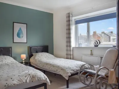 a bedroom with two beds and a window at Reed Cottage in Aspatria