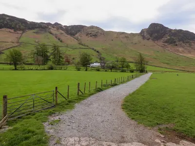 a gravel road in a field with mountains in the background at One Side House Farm in Ambleside