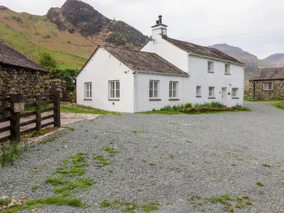 a white house with mountains in the background at One Side House Farm in Ambleside