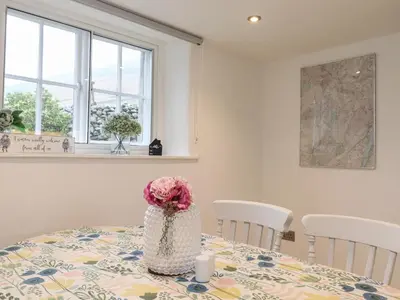 a room with a table with a flower on it at Two Side House Farm in Ambleside