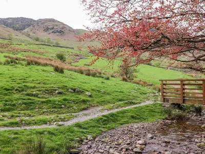 a bench sitting on a hill next to a stream at Two Side House Farm in Ambleside