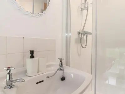 a white bathroom with a shower and a sink at Two Side House Farm in Ambleside
