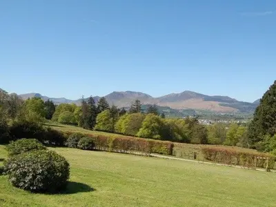a green field with trees and mountains in the background at Bramble Cottage perfect for a relaxing romantic break in Keswick in Keswick