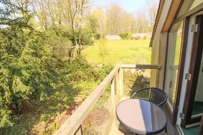 a balcony with a table and a chair on a porch at The Gardeners Cottage, Hutton John is a luxurious cottage with hot tub 10 minutes from Lake Ullswater in Penruddock