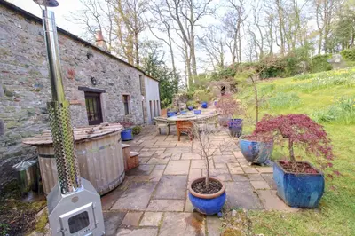 a patio with a table and potted plants in a yard at The Gardeners Cottage, Hutton John is a luxurious cottage with hot tub 10 minutes from Lake Ullswater in Penruddock