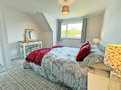 a bedroom with a bed and a desk and a window at Driftwood Cottage in Portpatrick