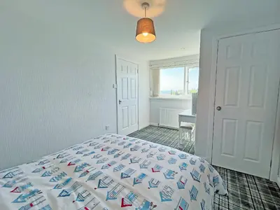a bedroom with a bed and a desk and a window at Driftwood Cottage in Portpatrick