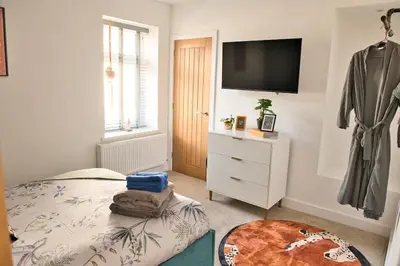 a bedroom with a bed and a dresser with a television at Quirky & Comfortable Residence in Workington