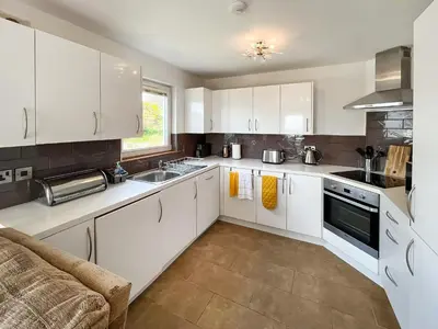 a kitchen with white cabinets and a sink at Sandpipers in Portpatrick