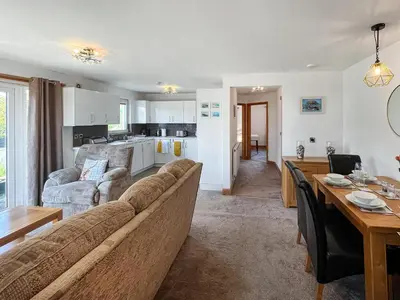 a living room and kitchen with a couch and a table at Sandpipers in Portpatrick