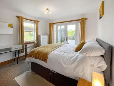 a bedroom with a large bed and a window at Sandpipers in Portpatrick