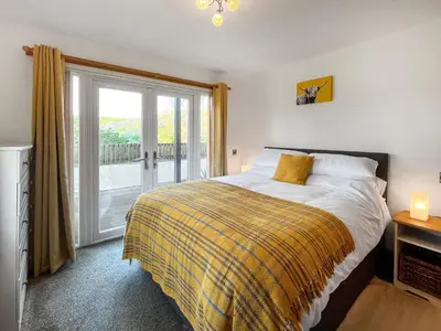 a bedroom with a bed and a large window at Sandpipers in Portpatrick