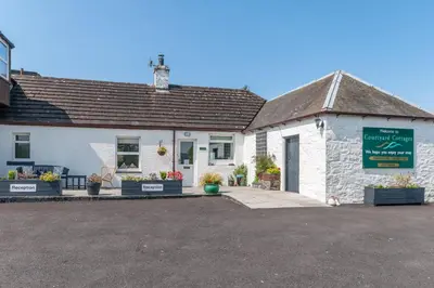 a white building with a sign in front of it at Courtyard Cottages, Barn Cottage in Wigtown