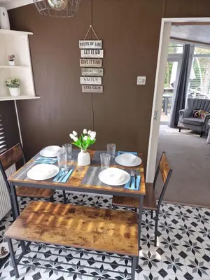 a dining room table with plates and flowers on it at The Forest Cabin Holiday Home 15 in Ballantrae