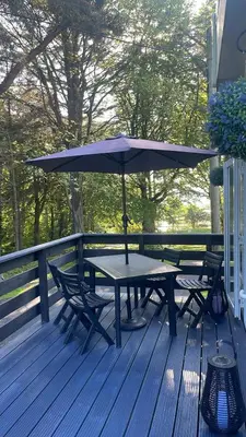 a picnic table with an umbrella on a deck at The Forest Cabin Holiday Home 15 in Ballantrae