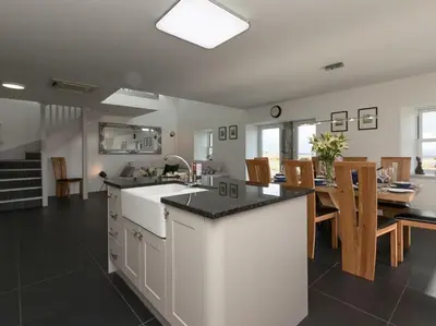 a kitchen and dining room with a table and chairs at Cot Cottage - Panoramic Views & Hot Tub! in Castle Douglas