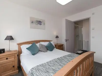 a bedroom with a large wooden bed with blue pillows at Cot Cottage - Panoramic Views & Hot Tub! in Castle Douglas