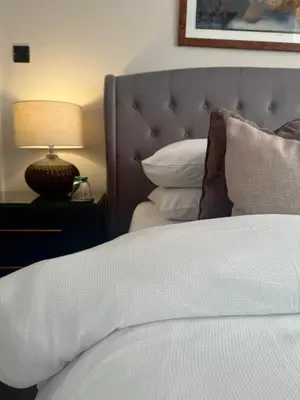 a close up of a bed with a lamp and pillows at Shemara rooms in Keswick