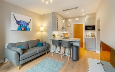 a living room with a couch and a kitchen at Gingerbread Nook in Grasmere