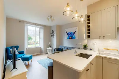 a kitchen with a sink and a living room at Gingerbread Nook in Grasmere