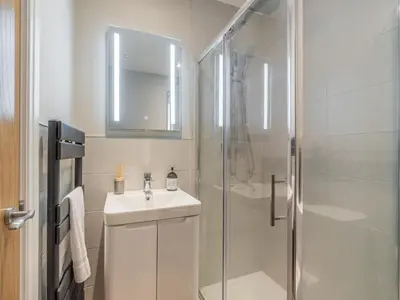 a white bathroom with a sink and a shower at Gingerbread Nook in Grasmere