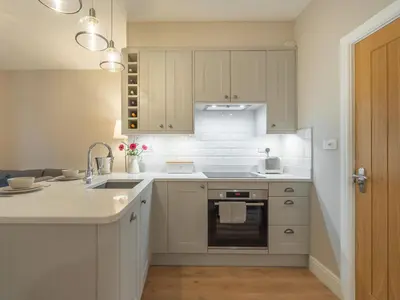 a kitchen with white cabinets and a sink at Gingerbread Nook in Grasmere