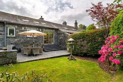 a patio with an umbrella in the yard of a house at Grey Crag Barn in Grasmere