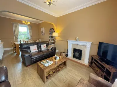 a living room with a leather couch and a fireplace at Beautiful House With Stunning Views Kirkcudbright - Pass the Keys in Kirkcudbright