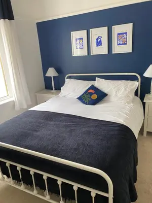a blue bedroom with a bed with a blue wall at Caerlaverock Cottage in Prestwick