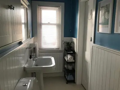 a white bathroom with a sink and a window at Caerlaverock Cottage in Prestwick