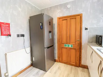 a kitchen with a refrigerator and a wooden door at Largieholm in Mauchline