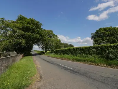 an empty road with trees on the side of the road at Largieholm in Mauchline
