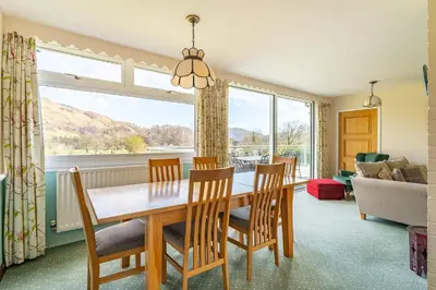 a dining room with a table and chairs and a large window at Le Tholonet in Grasmere